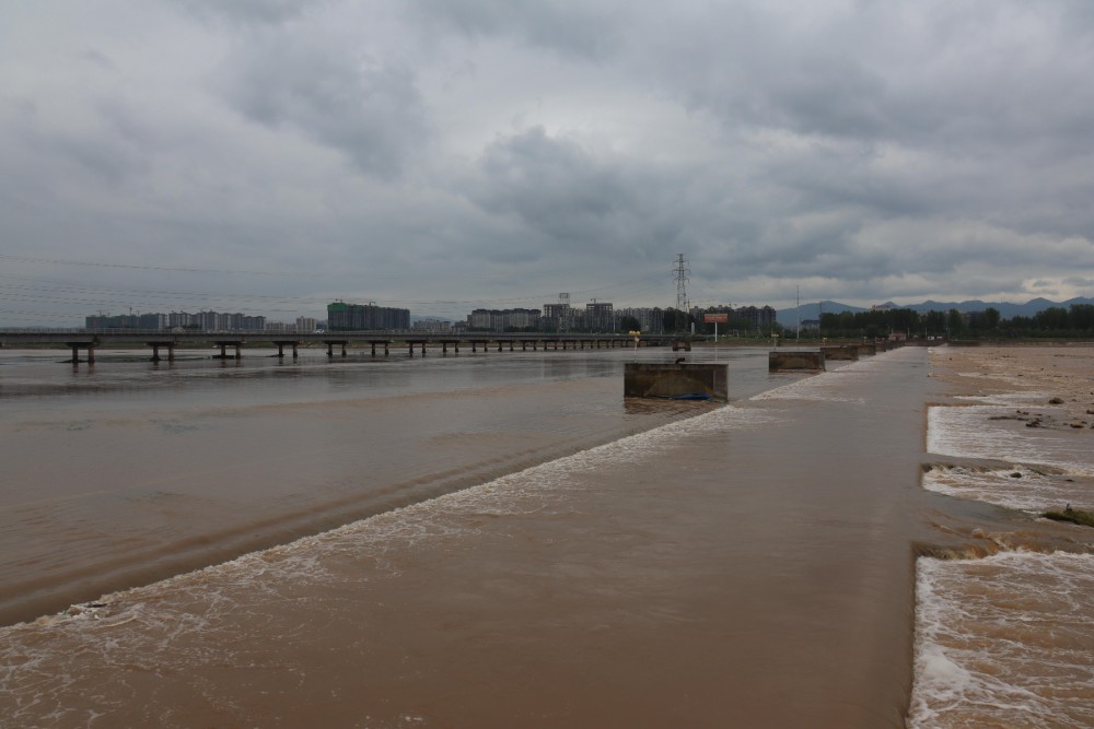 8月31日下午4时许,泥黄色的洪水流过汝州市北汝河4号橡胶坝.