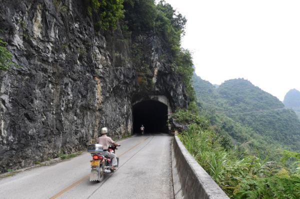 村民骑行穿越广西都安瑶族自治县澄江镇境内的一处山区公路隧道(2015