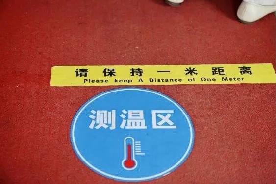 在入口处,门外有口罩自助售卖机,地上贴有"一米线"和测温点的标识.