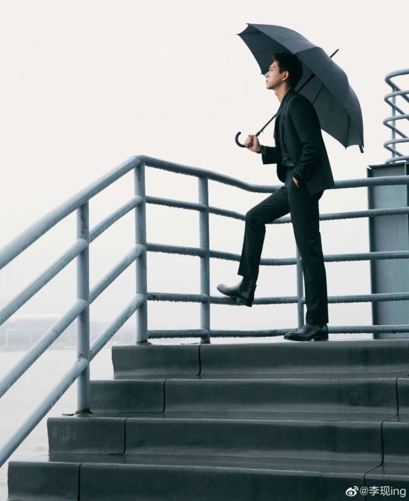 穿着全套得体的黑西服,撑着伞漫步在雨中的天台上的李现,让人回忆起19