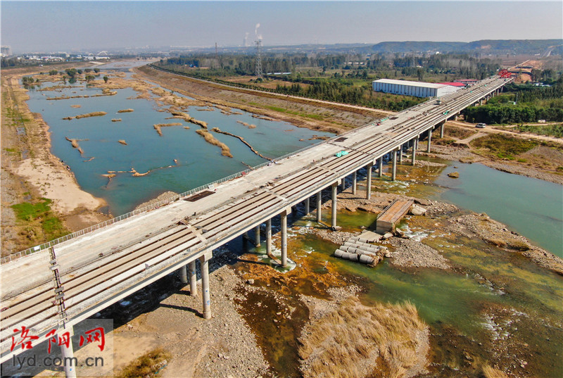 18日,在建设中的新(安)伊(川)高速公路伊川县境内,工人们正在横跨伊河