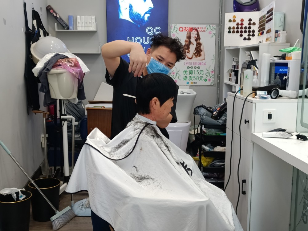 先用喷水壶把头发喷湿,然后是剪刀,推子,吸发器,理发师用