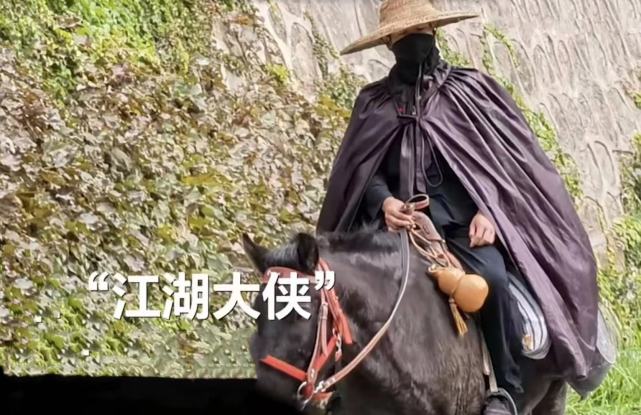 身着黑色披风,头戴斗笠,骑着一匹黑色马穿行在道路上,俨然"江湖大侠"