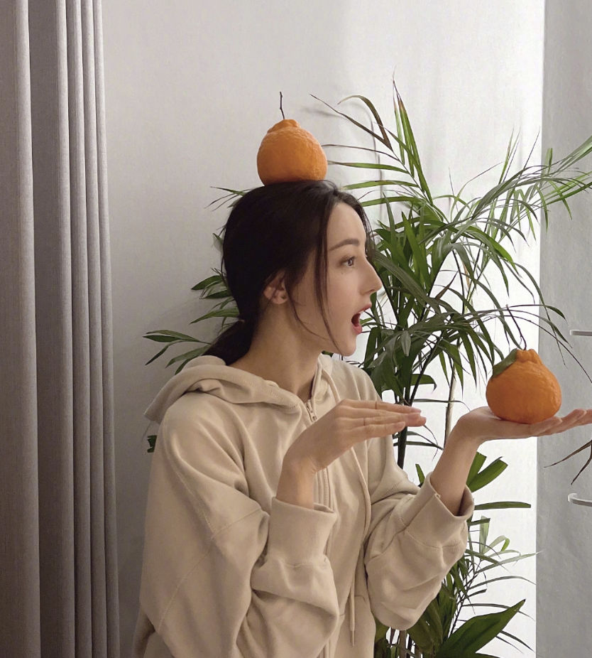 迪丽热巴晒生活照将橘子放在头顶搞怪摆拍表情多变古灵精怪