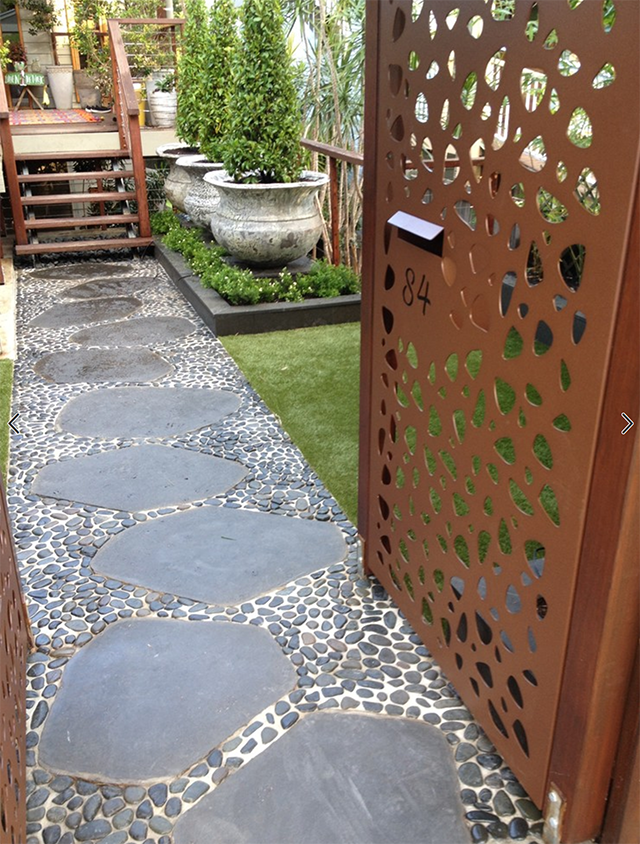 这是一个面积非常小的花园,花园设计很简单,地面铺设了石板石子路和