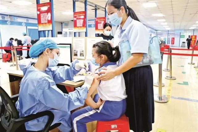 在西乡会堂大型临时接种点,小学生在父母的陪伴下接种新冠疫苗.