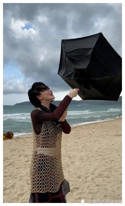 照片中,张馨予紧紧拽着被吹翻的雨伞,发型已经完全被风吹乱,表情也是