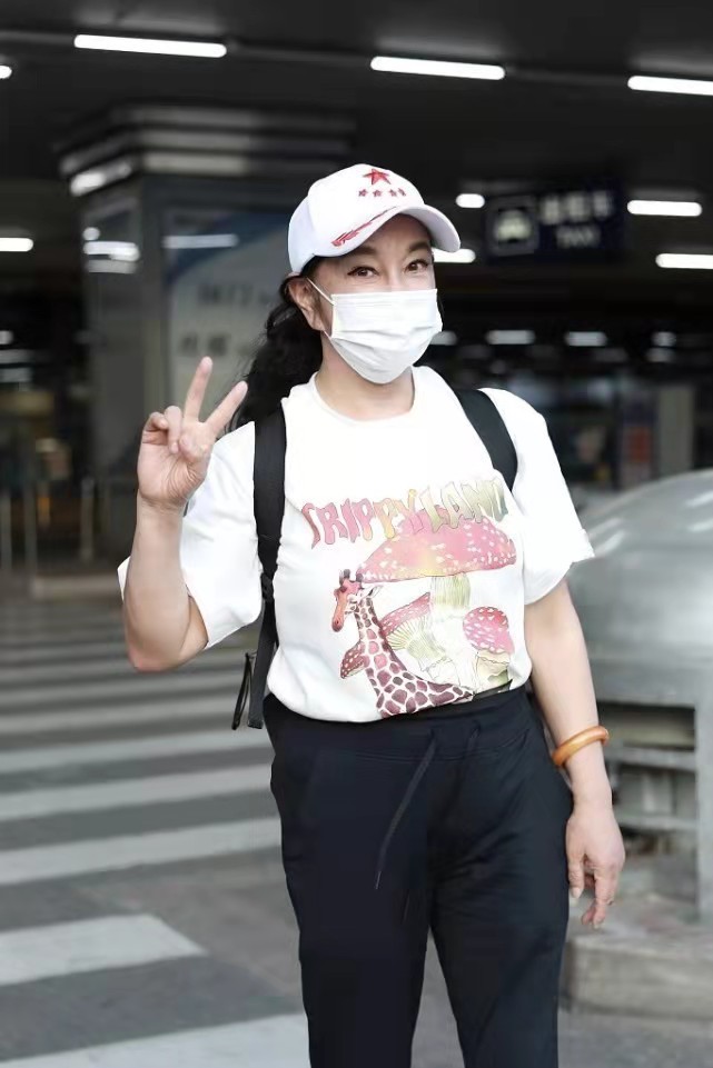 66岁刘晓庆还不服老，穿粉色印花T恤配黑裤走机场，俏皮减龄瑞典罗克赛特