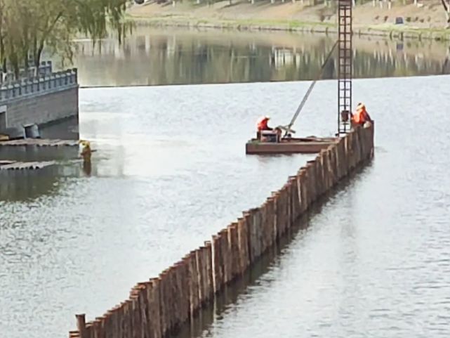 准备搭建挡水围堰河中已经有插好的木桩此处正是施工现场围挡上悬挂着