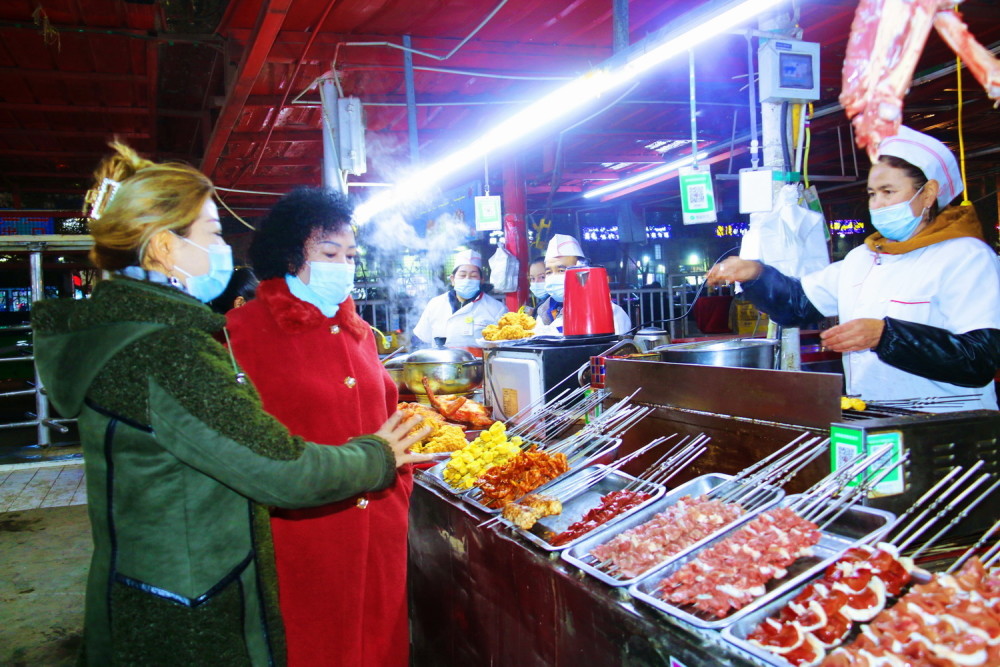 12月8日,库车市乌恰镇居民在彩虹综合市场的夜市购买美食.