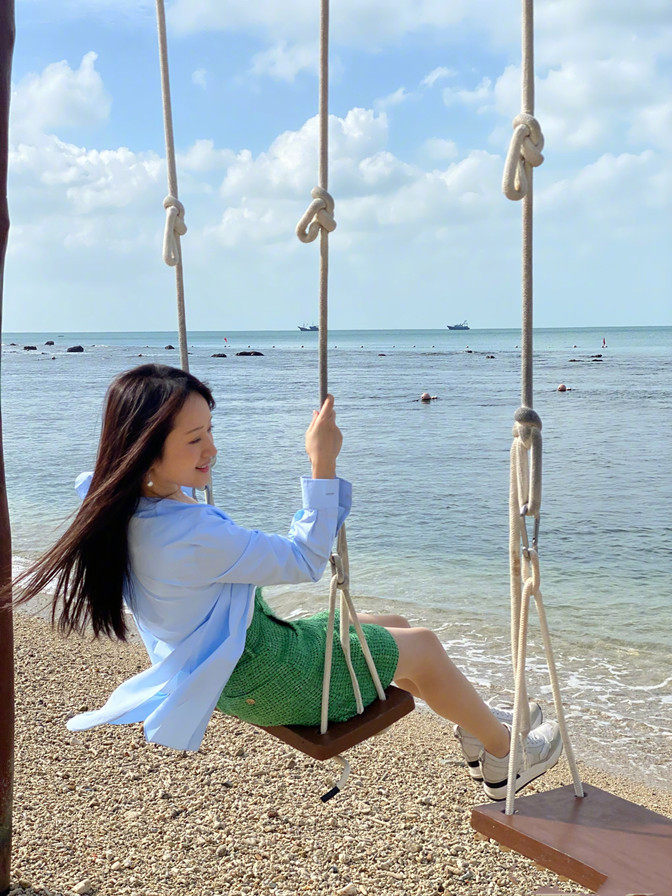 杨钰莹海边喝红酒惬意人生穿荷叶边衬衫戴报童帽50岁皮肤嫩得像小姑娘