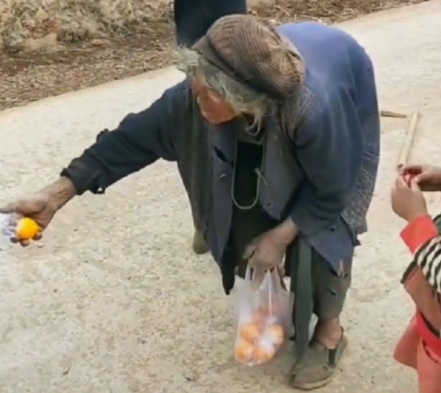 四川孤寡老人身形佝偻衣衫褴褛,仍给孩子们分橘子吃