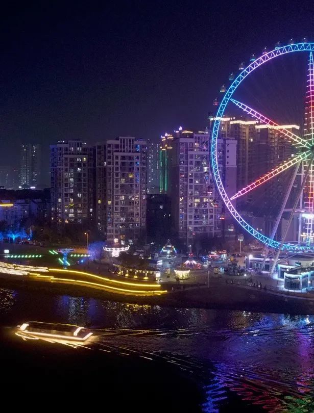 摩天轮上灯光色彩绚丽,灯光变幻下塑造出一种连续流动的空间;游船航行