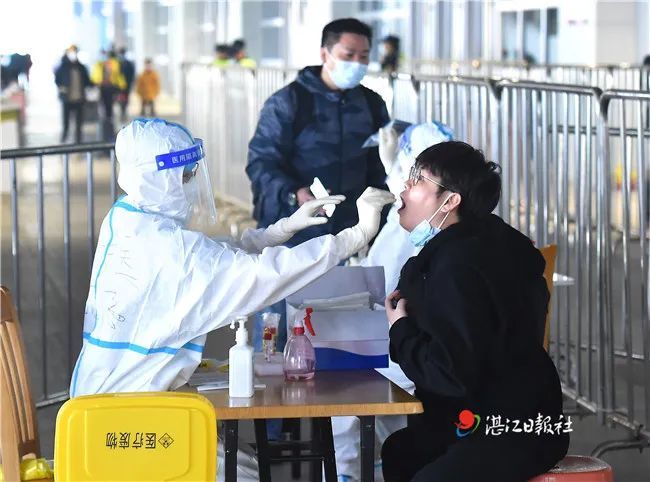 春运首日,在湛江西站出站口,医务人员正为刚到站的乘客做核酸检测.