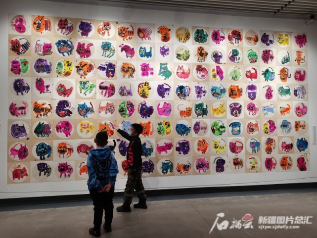 小朋友在参观童画新年——首届新疆少儿美术作品展.