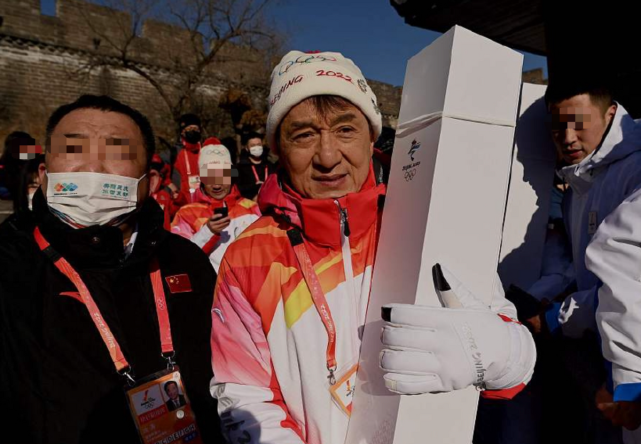 67岁成龙当冬奥火炬手紧抱火炬盒冻到瑟缩歪头与人合影无架子
