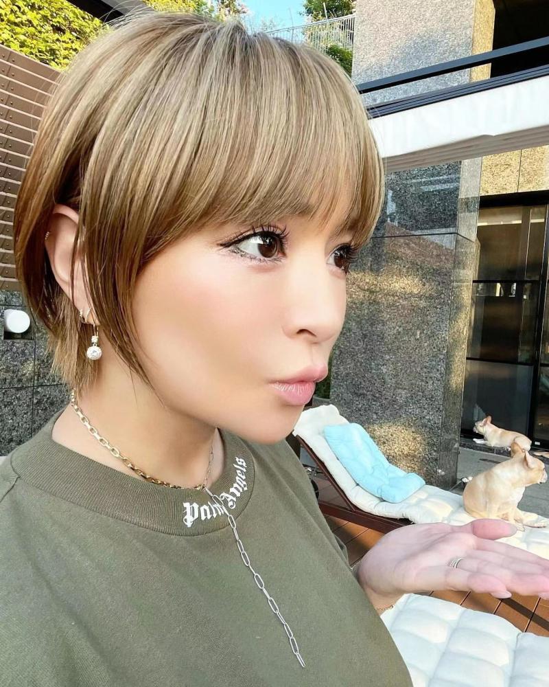 滨崎步坐在别墅庭院的石台上摆拍,一身潮牌粉色印花卫衣套装造型休闲