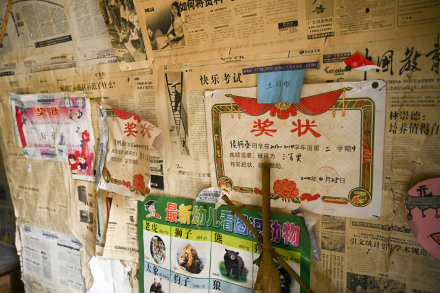 内除了张贴的报纸外,两侧的墙壁上还残留着儿童识字贴图和孩子的奖状