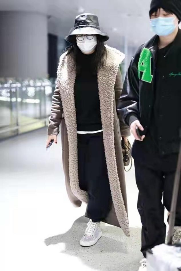 李湘身穿毛绒大衣很气派,头戴黑帽像魔术师,走路潇洒