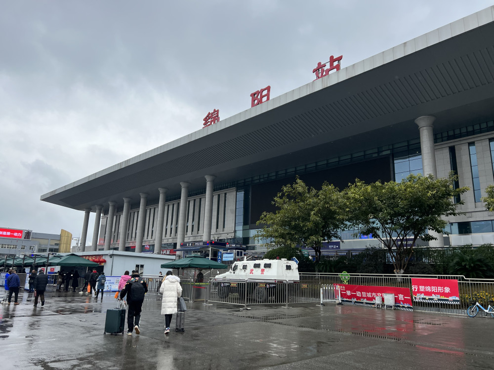 在绵阳火车站入口处,乘客需通过闸机扫码并测温后,方可进站.