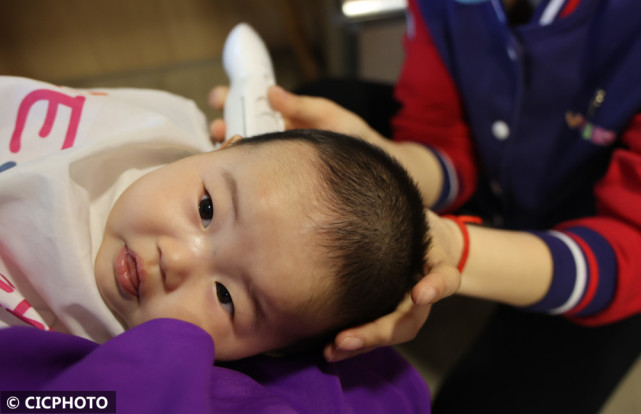 2022年3月4日,在江苏省连云港市赣榆区一家理发店,理发师在给一名小