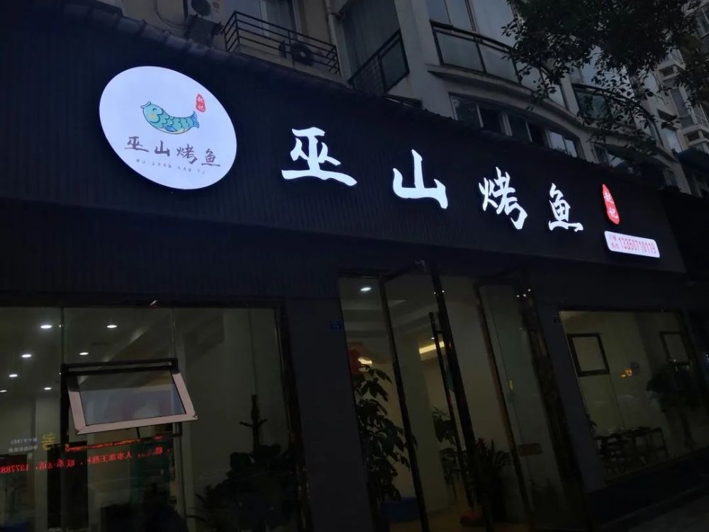 来到赵记巫山烤鱼店外,暗色的牌匾上镶嵌着巫山烤鱼明亮的招牌,别样