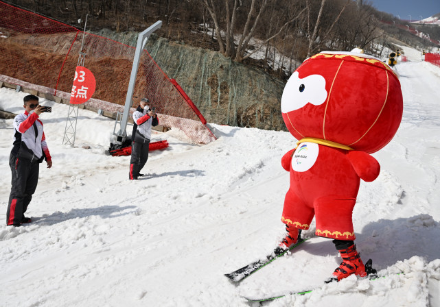 雪容融在延庆国家高山滑雪中心滑雪时与工作人员互动(3月10日摄)