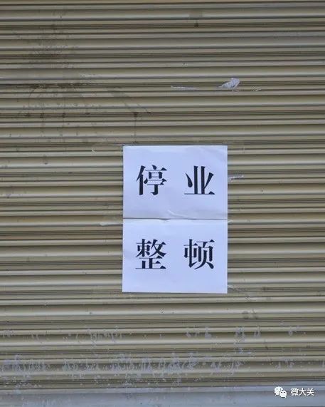 疫情未结束,防护勿松懈现场,工作人员将店门关闭,并贴上"停业整顿"