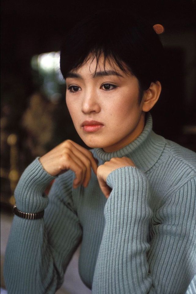 巩俐年轻时穿着一件雾霾蓝针织毛衣,温柔又时髦,眼神里满是故事,这件