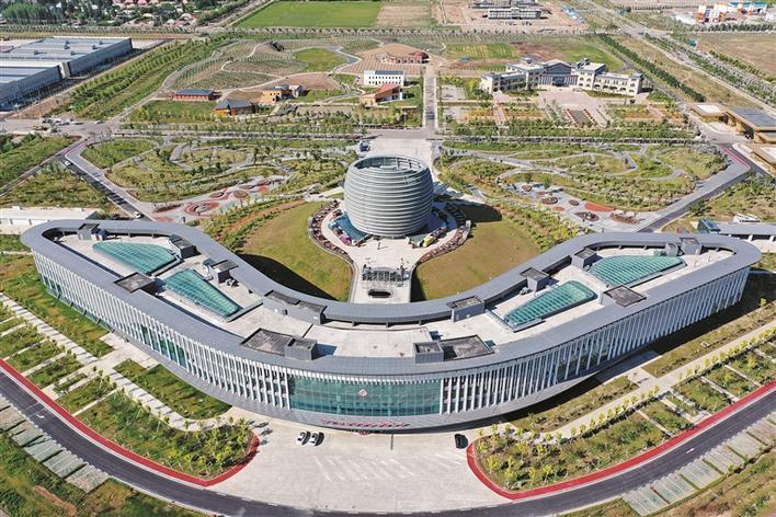 伊力特生态产业园鸟瞰.在伊力特生产车间,工人在给成品酒贴标签.