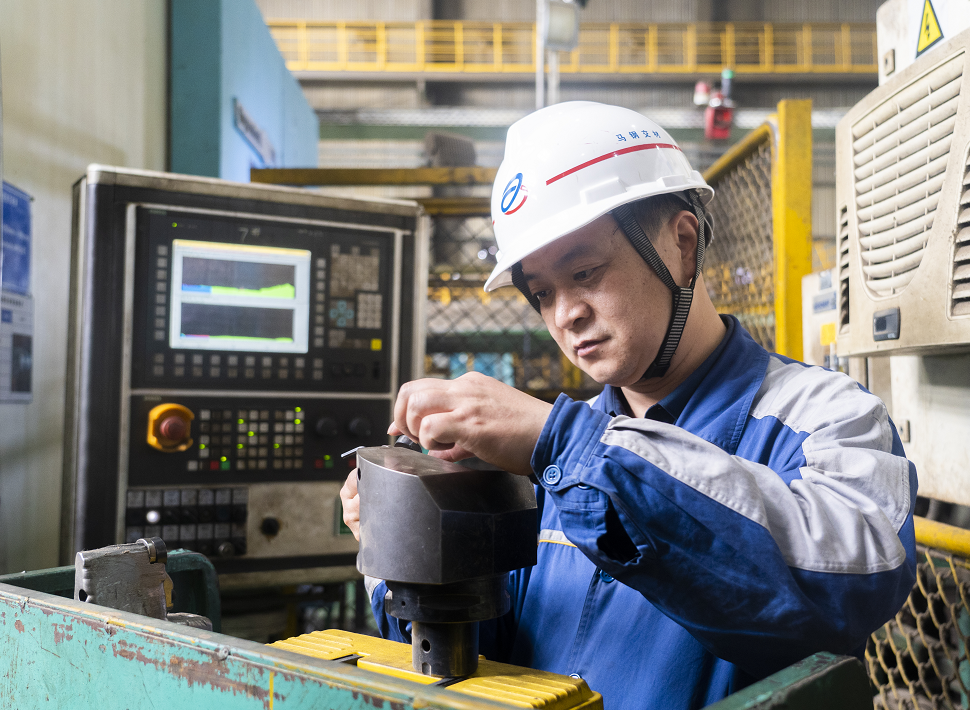 今年44岁的沈飞,头戴白色安全帽,身穿蓝灰相间的工作服,目不转睛地