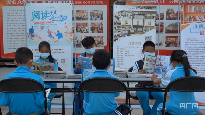 流动图书车旁的图书桌上看书(央广网发 岑巩县融媒体中心供图)"我们