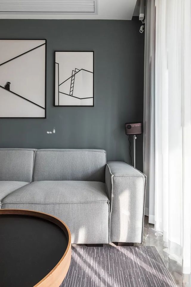 沙发墙在蓝灰色的空间基础,挂上极简线条的白底装饰画,侧边布置投影
