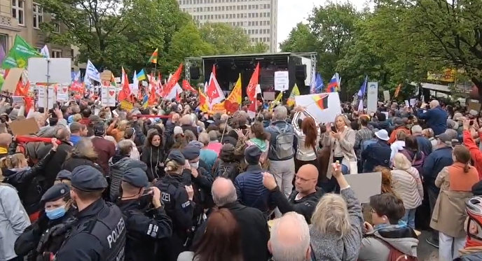 德国总理台上高声演讲支持乌克兰，示威者台下吹口哨高喊“战争贩子”