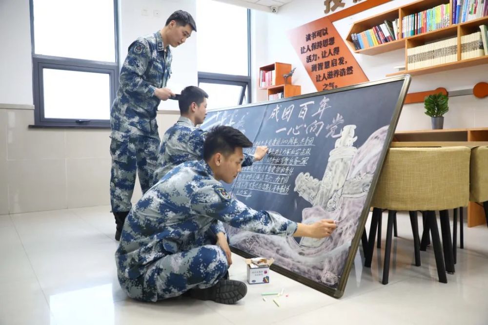 北部战区空军某部青年团员用彩色画笔勾勒"建团百年"主题板报,用铿锵