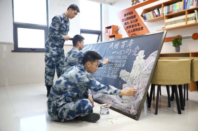 北部战区空军某部青年团员用彩色画笔勾勒"建团百年"主题板报,用铿锵