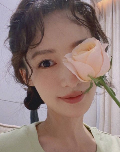 李沁晒双丸子头卷发自拍手拿鲜花对镜微笑