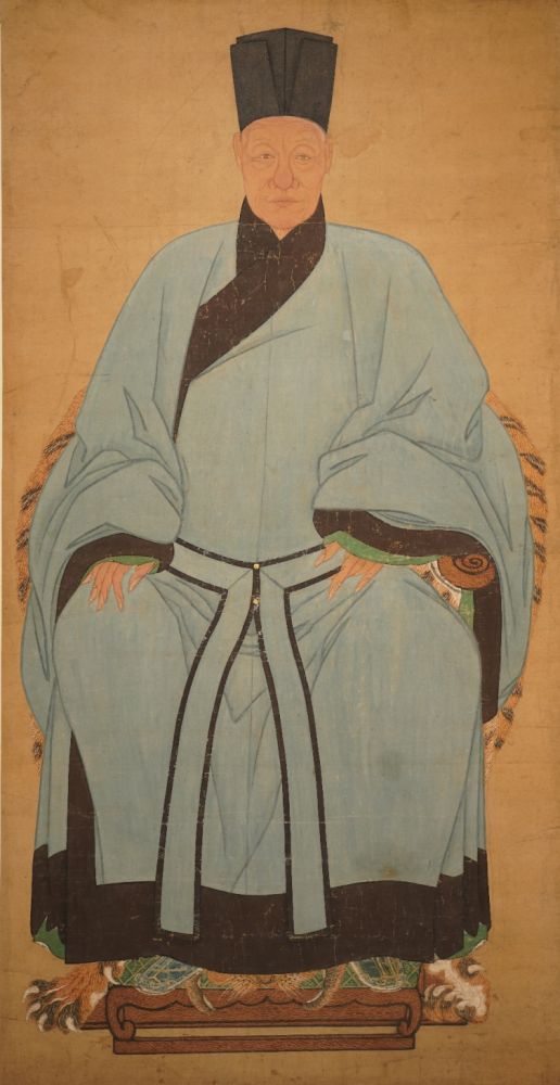 身着青色宽袖右祍大袍,目视观者,神态坦荡平和,显示出温文尔雅,睿智高