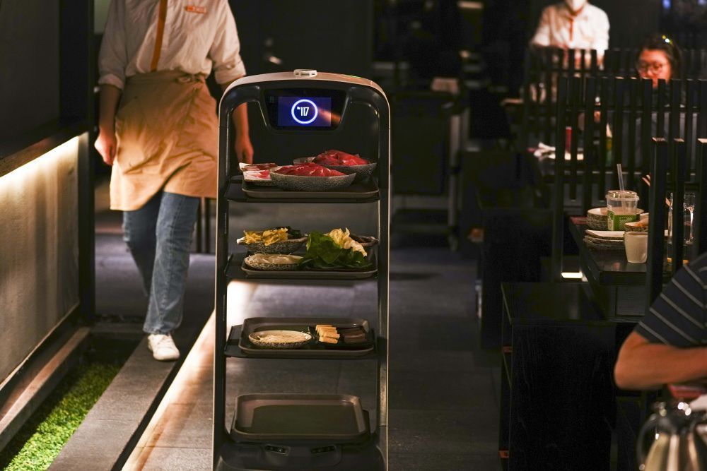 在长春市一家火锅店内,送菜机器人为顾客运送菜品(6月3日摄).