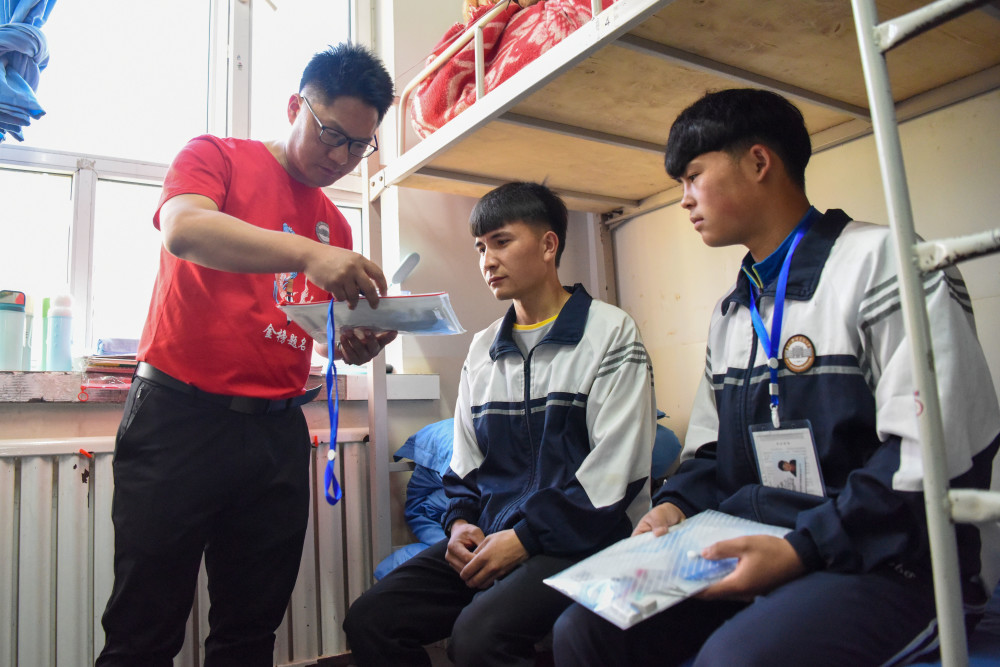 6月7日,在新疆阿克苏地区乌什县第一中学生活区,老师帮助即将参加高考