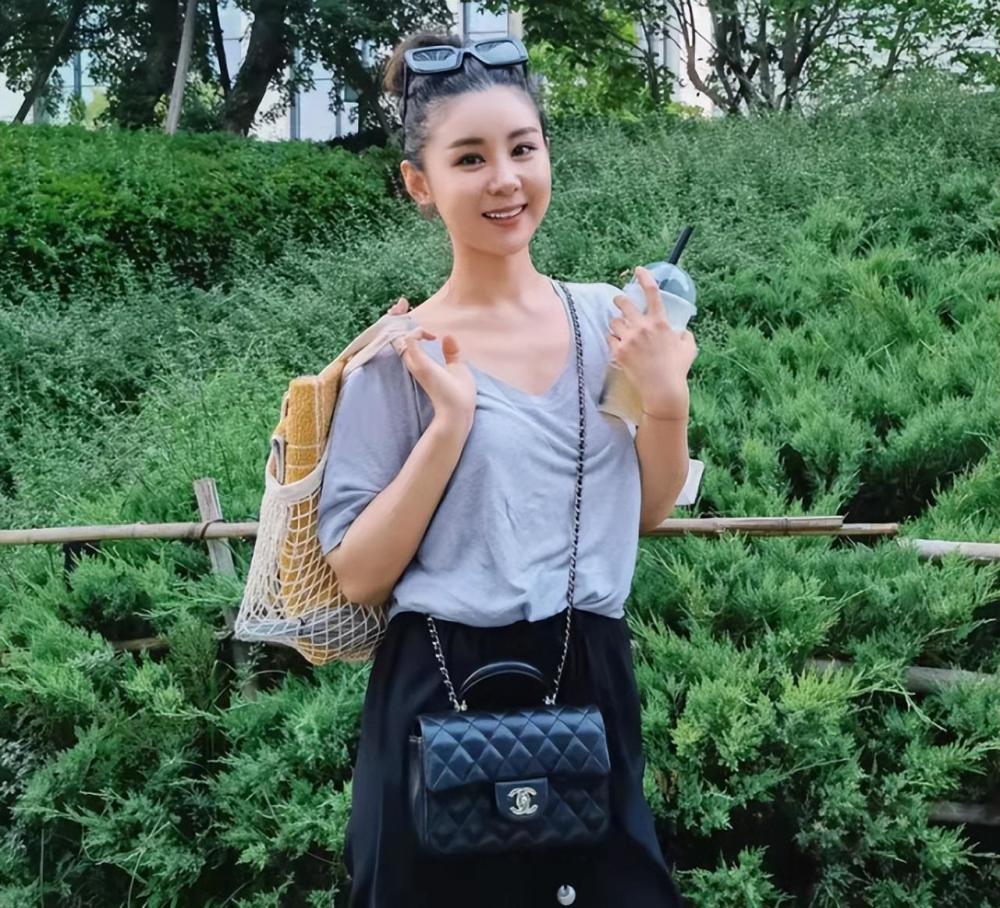 下图中,李小萌扎着丸子头,戴着墨镜,身穿低领款式宽松上衣搭配阔腿