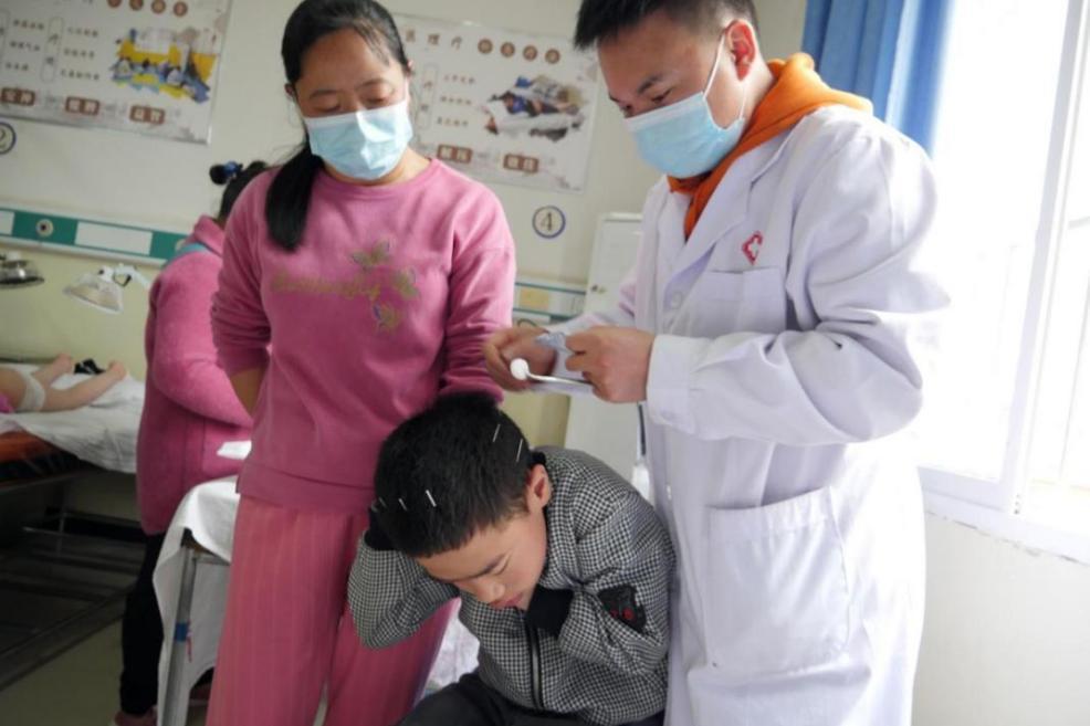 图为胡成芝陪儿子肖雷做针灸治疗.