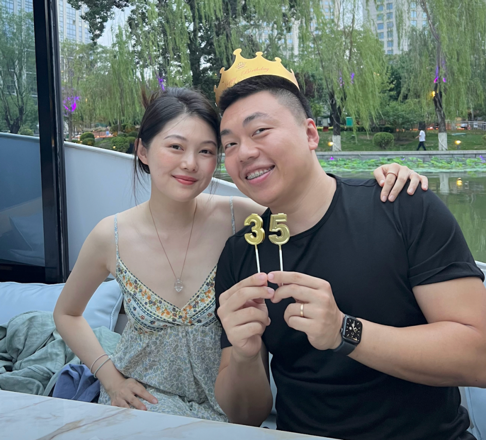 玩玩的老公林翰穿着黑色t恤,头上戴着生日帽,晚晚将手搭在林翰的肩膀