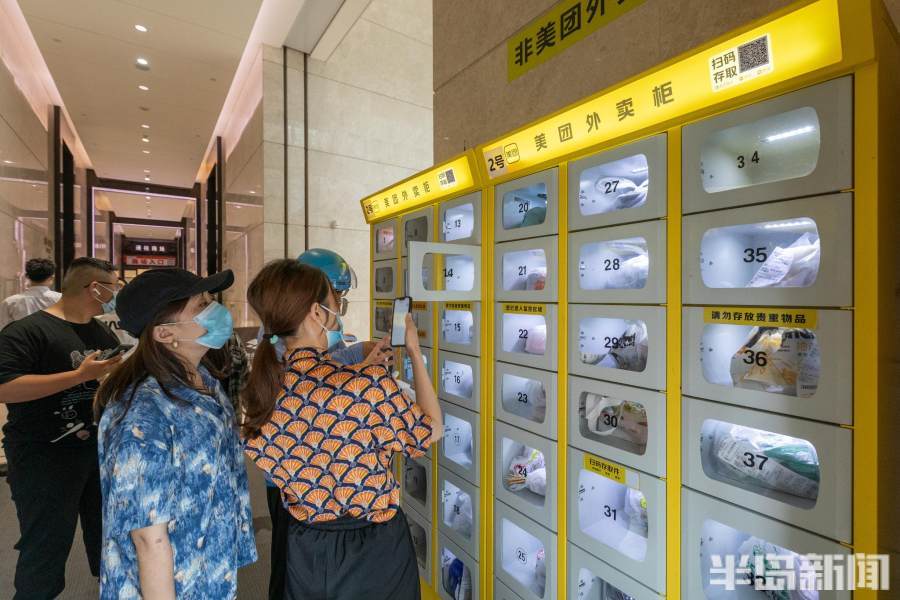 和顾客在卓越世纪中心3号楼下的外卖柜前存取外卖与"蜂巢"快递柜类似