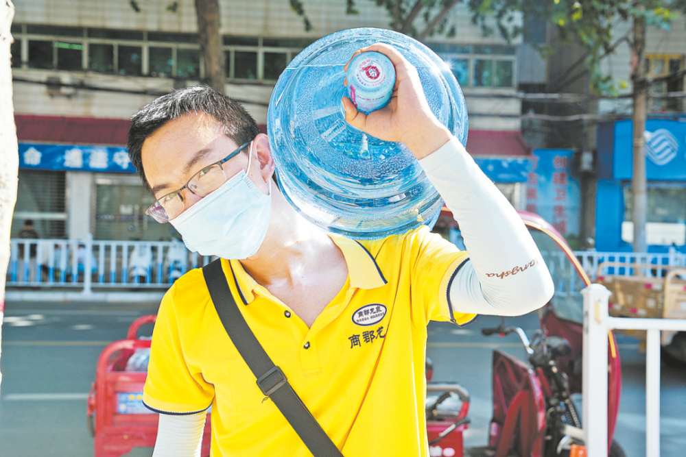 送水工王鹏飞扛着水桶上楼又下楼运送甘露,汗水湿透了他的每一寸