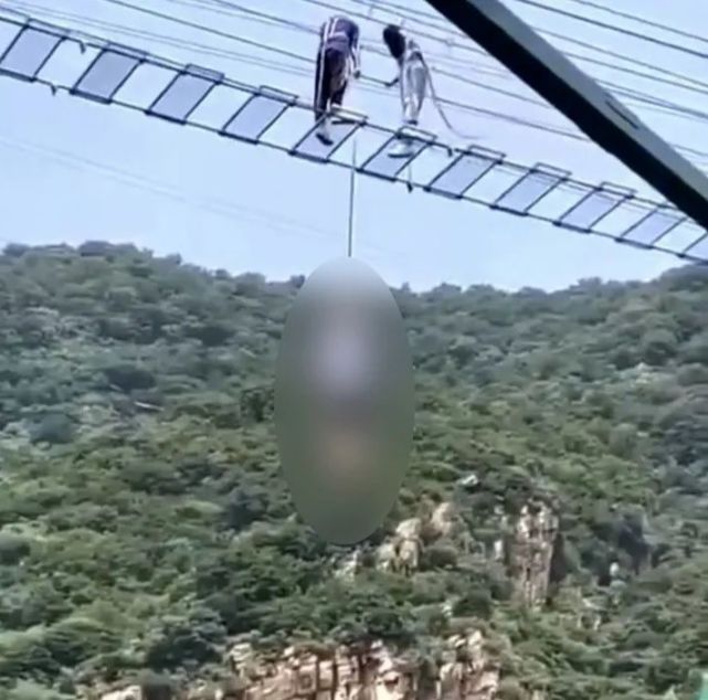 网传视频显示,1名游客被吊在玻璃吊桥下方,身体悬在半空.