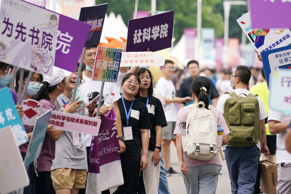 8月17日,在清华大学迎新点,学生举着院系牌迎接新生入学.