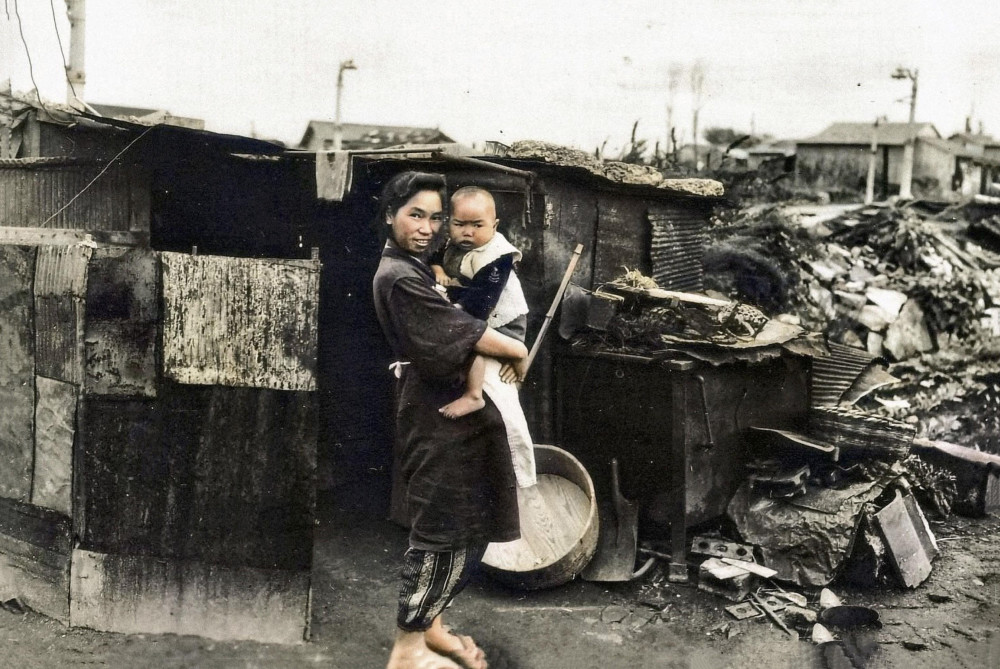 1945年8月在日本广岛拍摄的照片,一名妇女抱着小孩站在已经变成废墟的