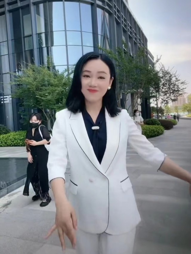 视频中,周群穿着一套白色西装,内搭黑色衬衫,妆容精致,干练大方,似乎