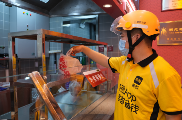 美团外卖骑手在蔡林记门店内取餐.